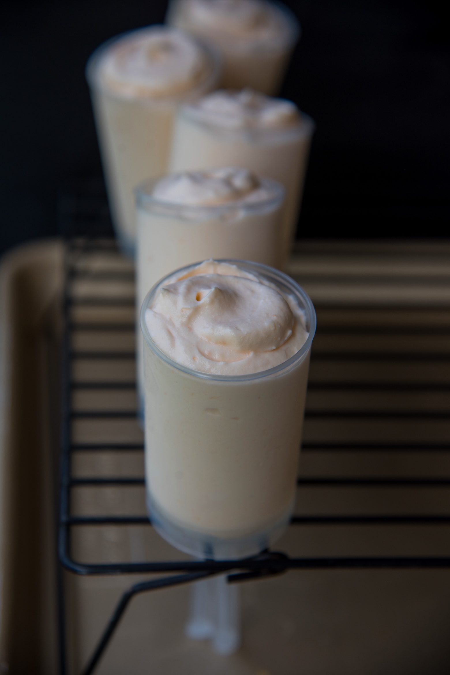 Several Creamsicle Bavarian Cream Push Pops in a row going front to back on a wire rack. Focus is on the first Creamsicle Bavarian Cream Push Pop