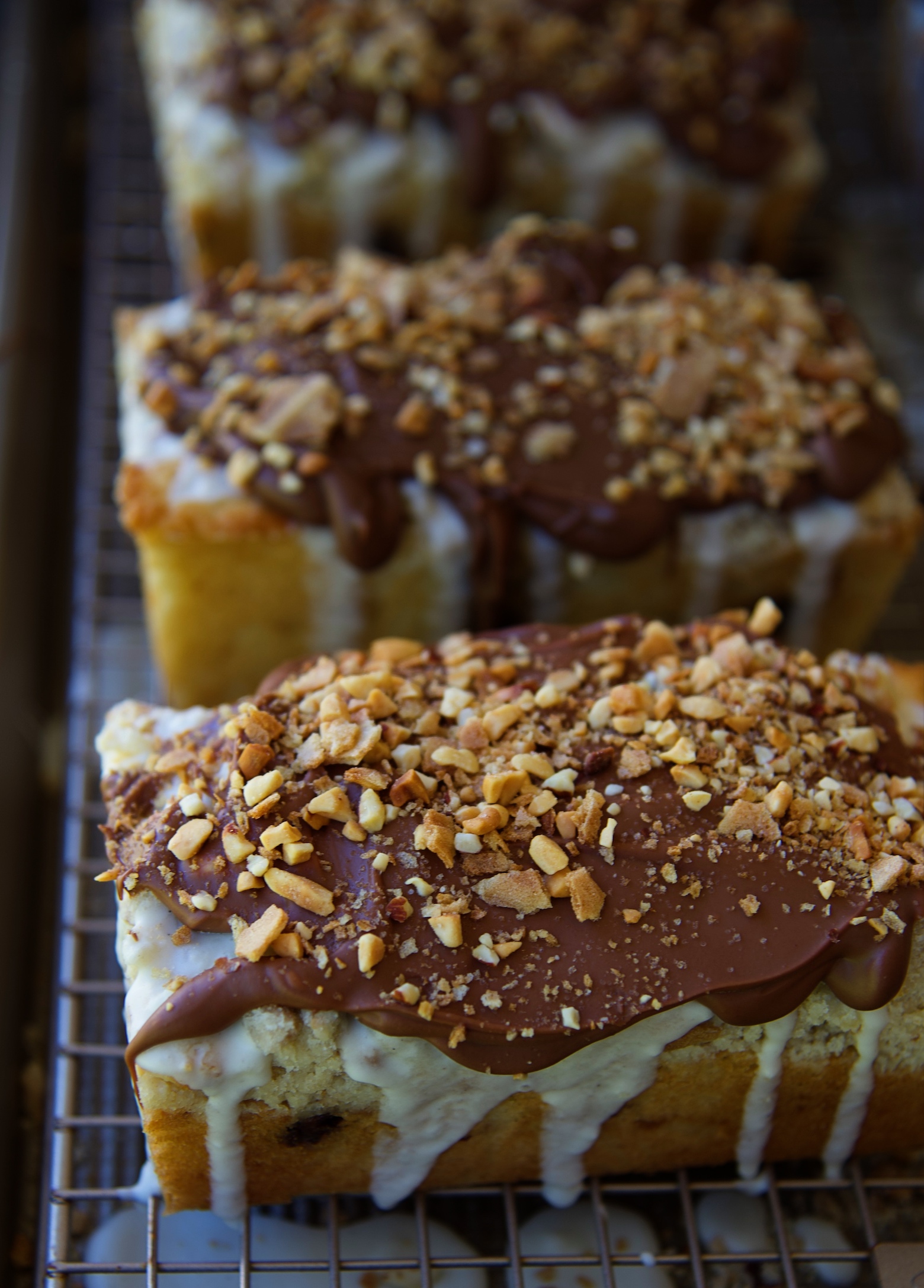 Three Glazed Drumstick Crumb Cakes on a wire rack with vanilla ice cream glaze dripping down. 