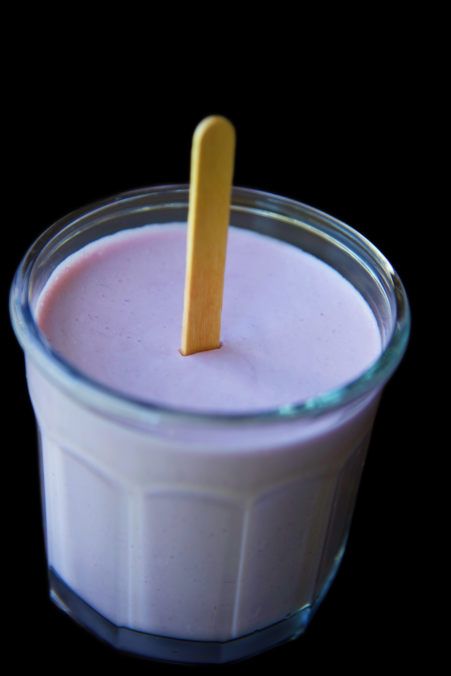 Glass jar filled with Grape Popsicle Jello with a popsicle stick coming out of it. 