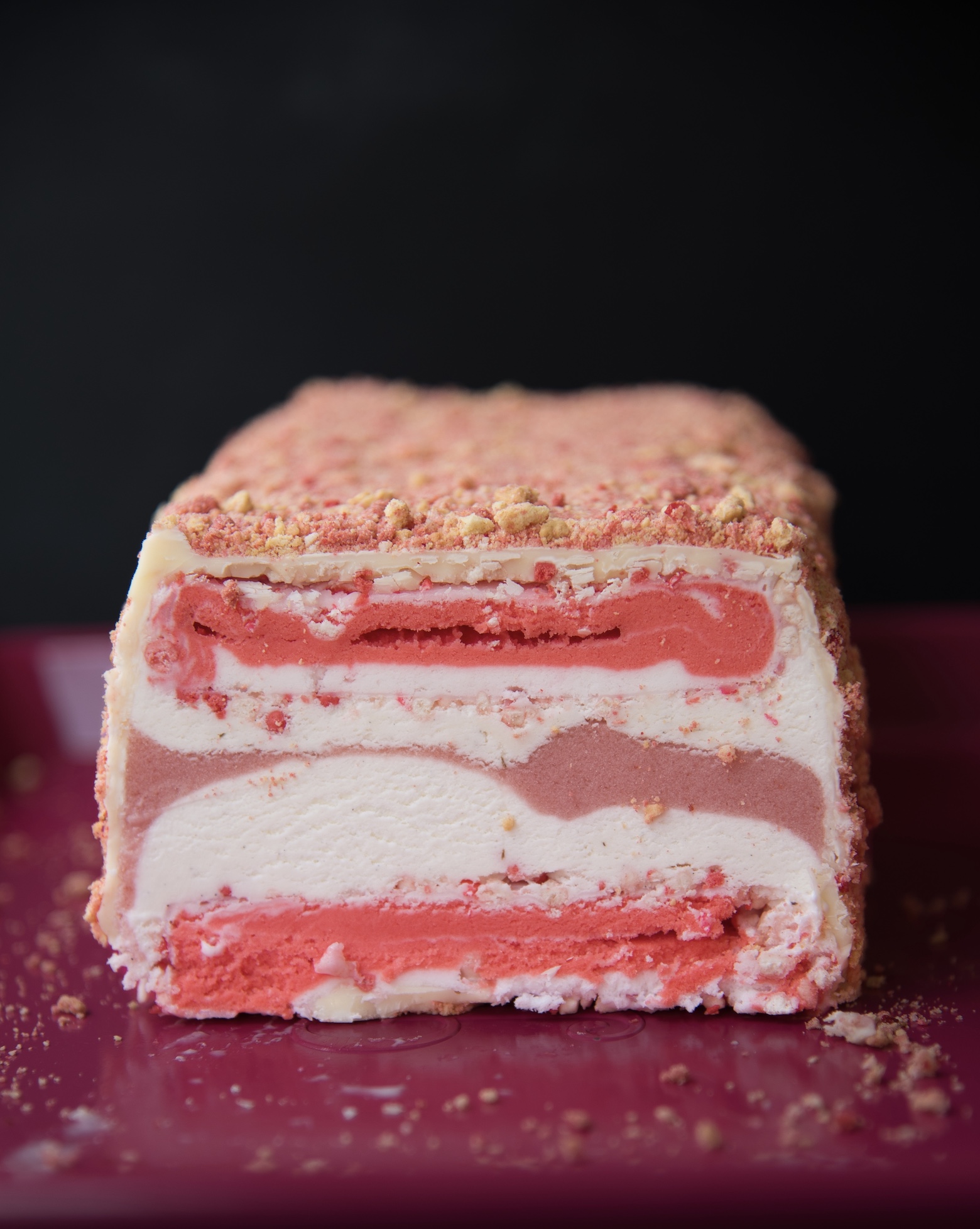 Strawberry Shortcake Ice Cream Terrine cut with the center exposed showing the layers of vanilla and strawberry ice cream. 