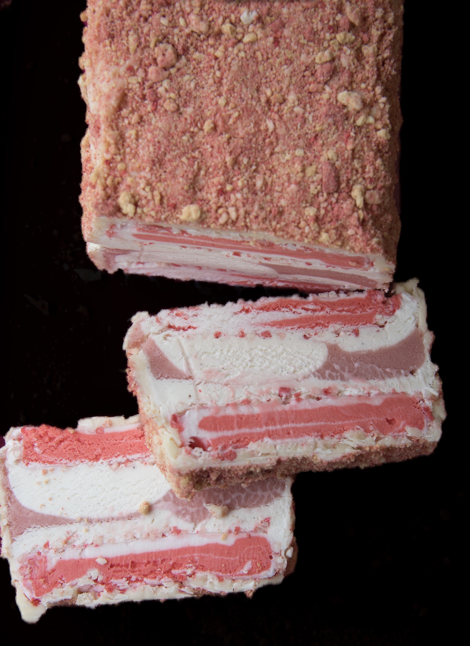 Overhead shot of the Strawberry Shortcake Ice Cream Terrine with two slices laying down exposing the pink and white layered colors of ice cream.