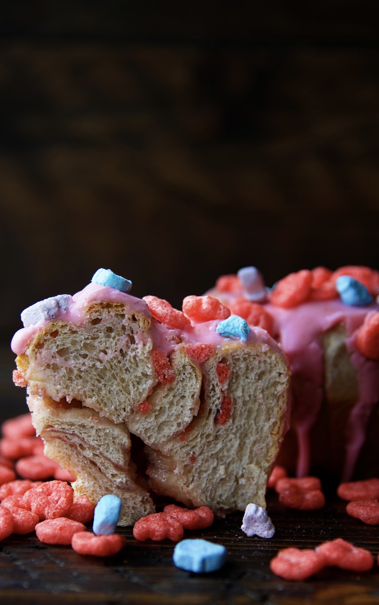 A Franken Berry Breakfast Bun cut in half to expose the filling with a full bun behind it. 