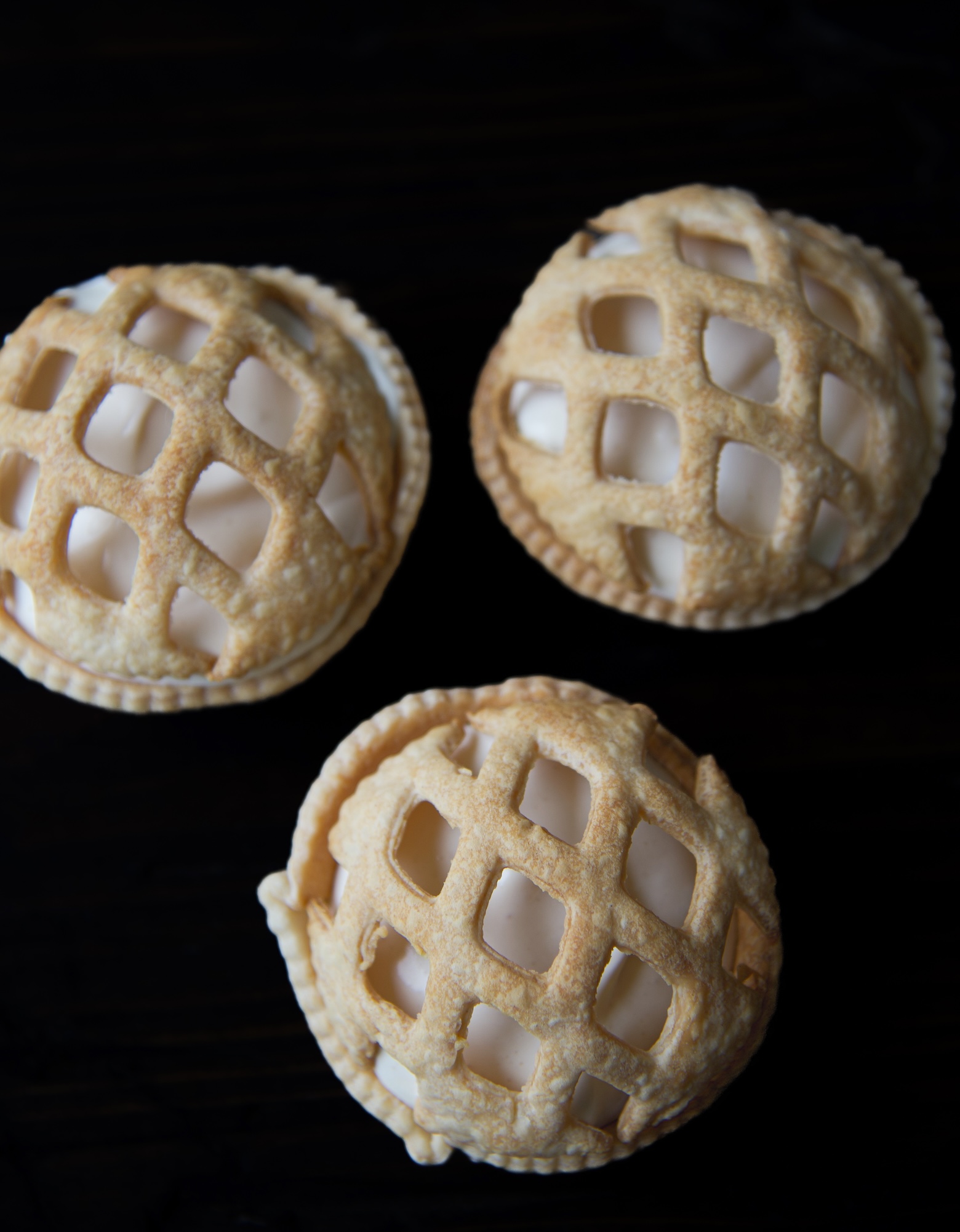 Overhead of three Apple Pie Pudding Shots in pie crust shells with a pie crust lattice dome on top. 