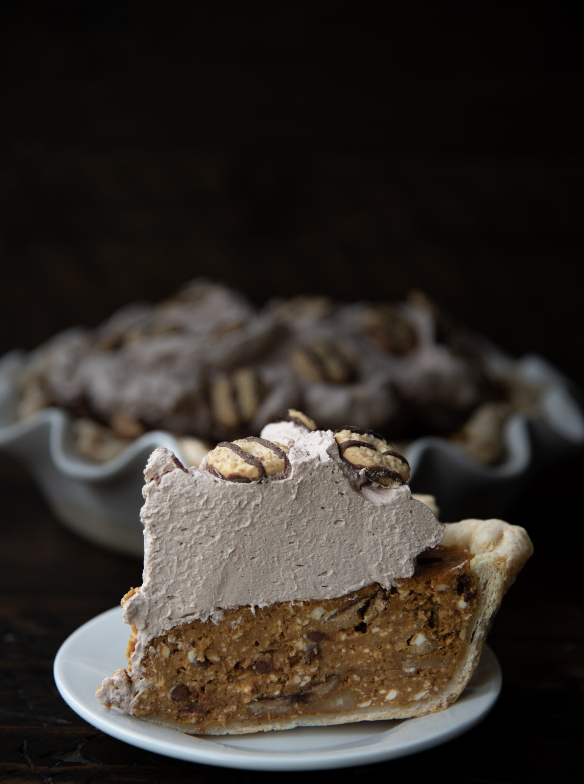 Side view of Fudge Cookie Pumpkin Pie in front of the remaining pie in background. 