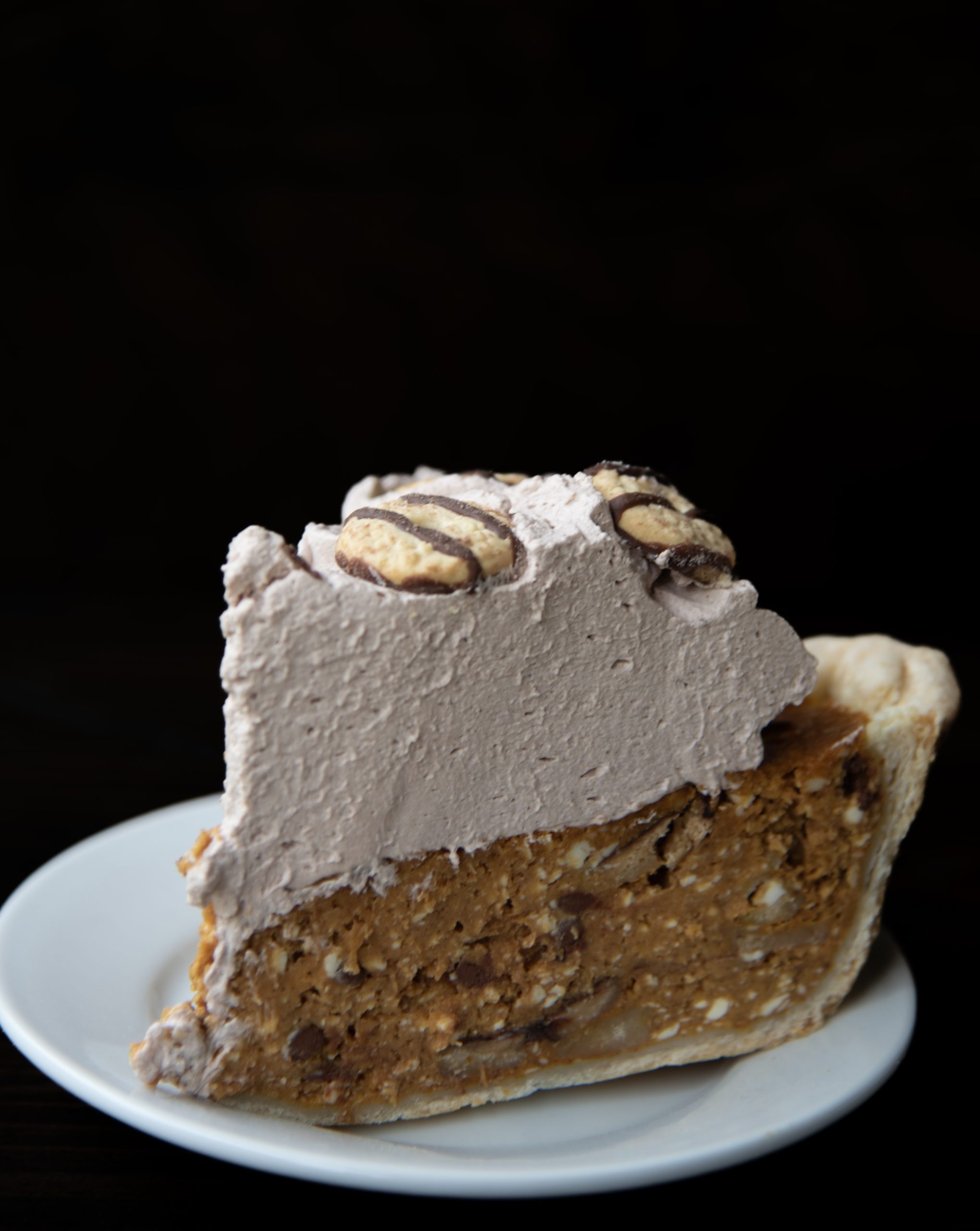 Close up of a slice of Fudge Cookie Pumpkin Pie where you can see the flecks of cookie pieces in the pie. 