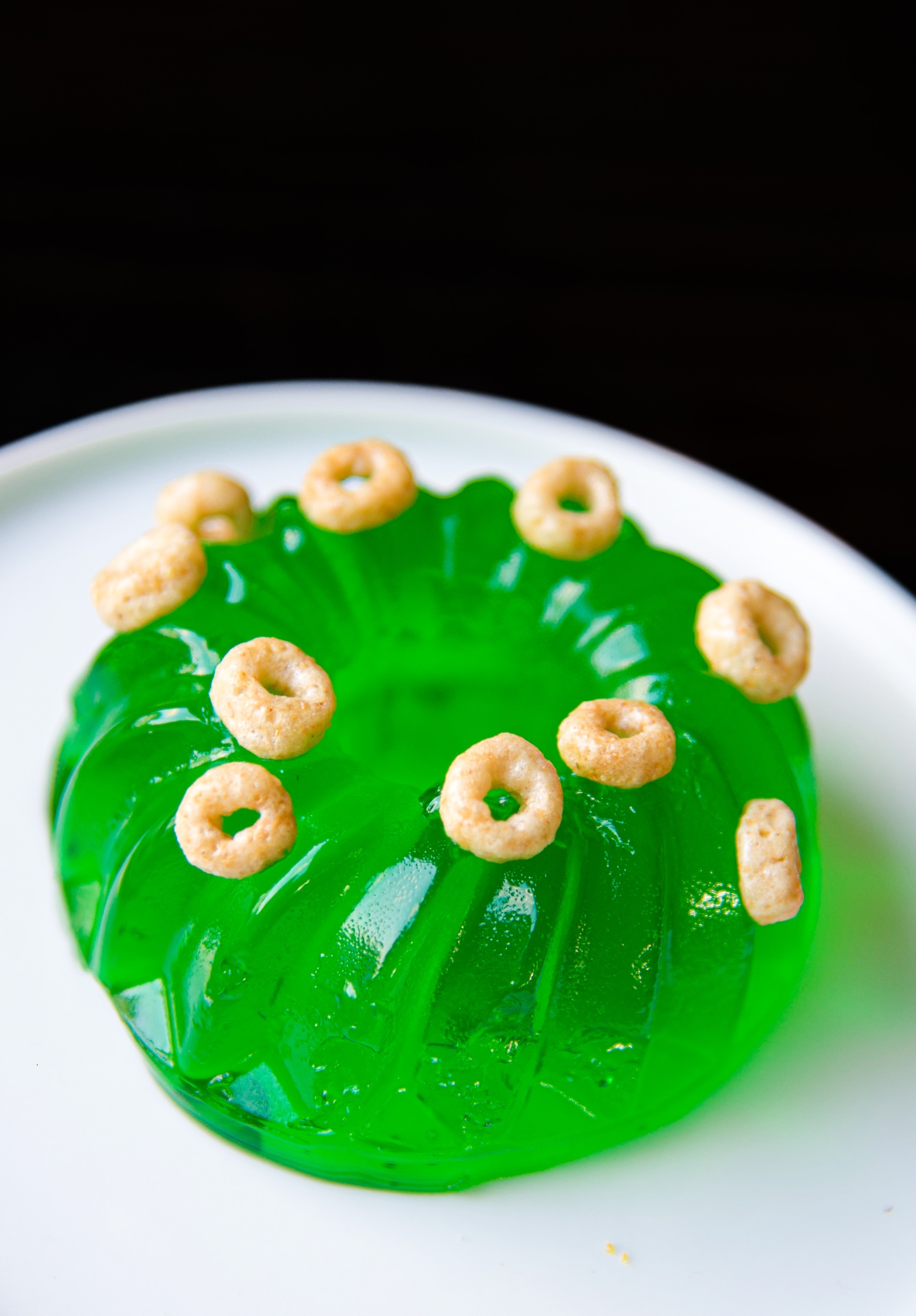 Close up of mini lime green jello shot with mini cereal on top. 